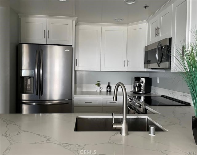 kitchen with appliances with stainless steel finishes, white cabinets, and light stone counters