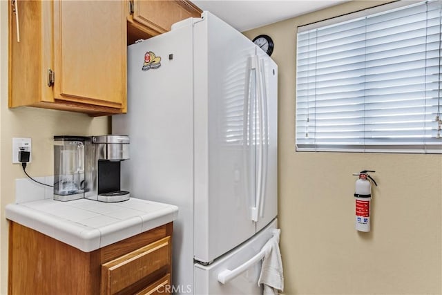 kitchen with white refrigerator and tile counters