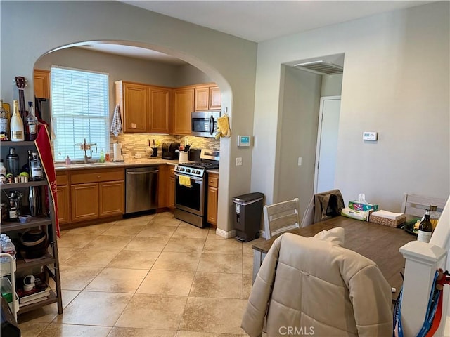 kitchen with light tile patterned floors, stainless steel appliances, backsplash, and sink