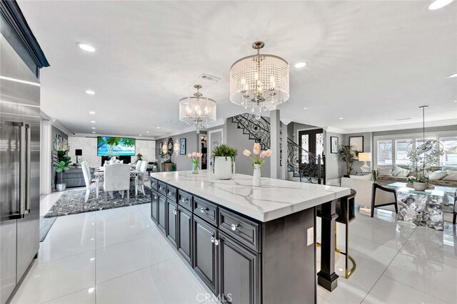 kitchen with light stone countertops, pendant lighting, a large island, a chandelier, and light tile patterned flooring