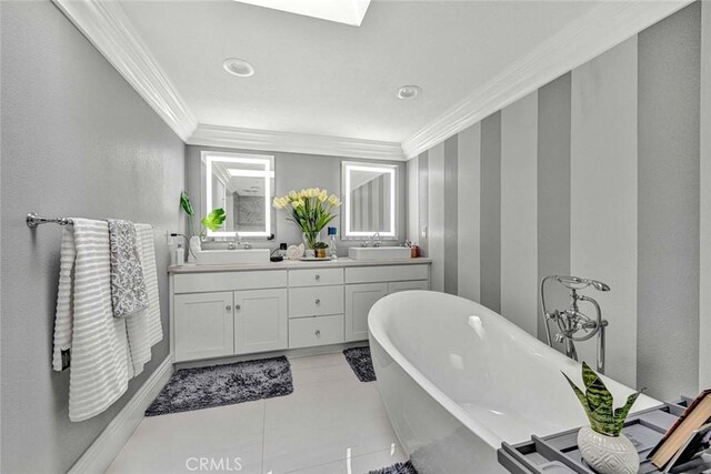 bathroom featuring tile patterned floors, vanity, a skylight, ornamental molding, and a bathing tub