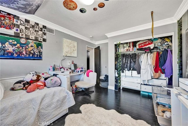 bedroom with a closet, crown molding, dark hardwood / wood-style floors, and a textured ceiling