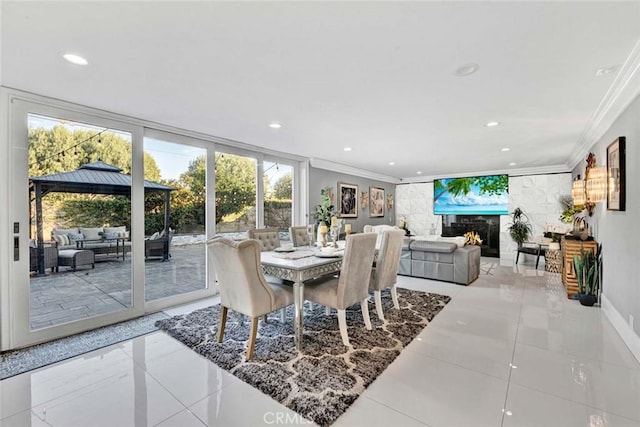 tiled dining area featuring crown molding, expansive windows, and a large fireplace