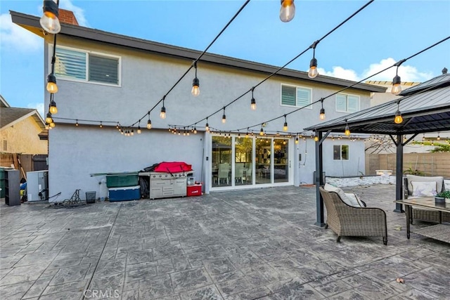 back of house featuring a patio area, outdoor lounge area, and a gazebo