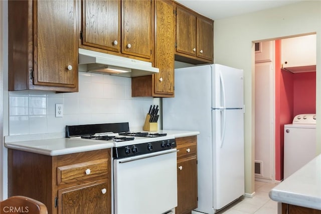 kitchen with washer / clothes dryer, white appliances, light tile patterned floors, and backsplash