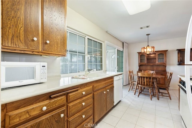 kitchen featuring white appliances, sink, hanging light fixtures, and light tile patterned floors