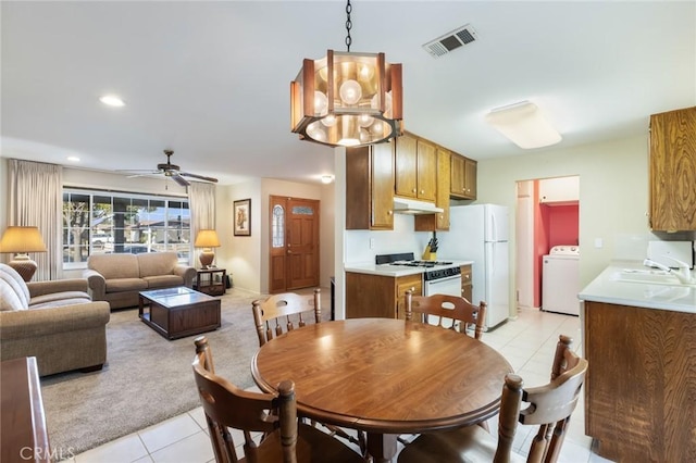 dining area with washer / clothes dryer, ceiling fan with notable chandelier, sink, and light tile patterned floors