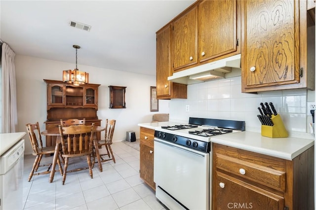 kitchen featuring white appliances, decorative light fixtures, light tile patterned floors, and backsplash