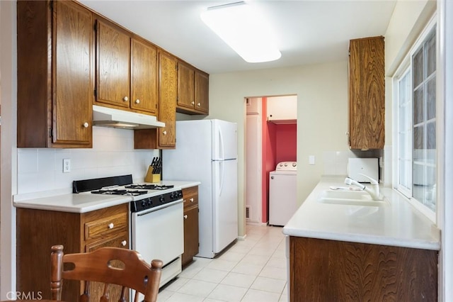 kitchen featuring sink, white appliances, tasteful backsplash, light tile patterned flooring, and washer / dryer