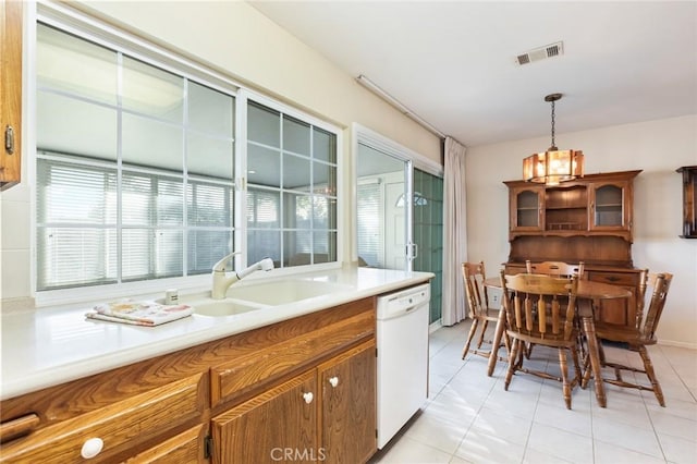 kitchen featuring pendant lighting, light tile patterned floors, white dishwasher, and sink