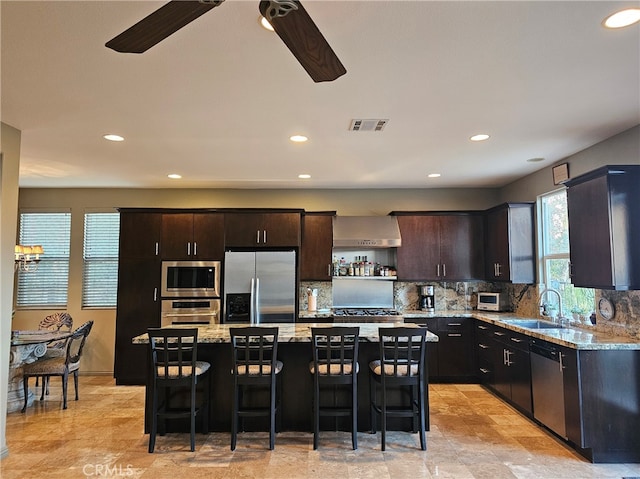 kitchen featuring visible vents, light stone counters, stainless steel appliances, a kitchen bar, and backsplash