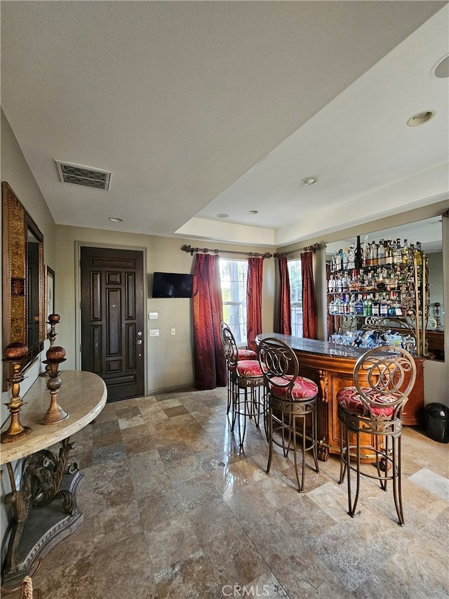 dining space featuring bar area and a raised ceiling