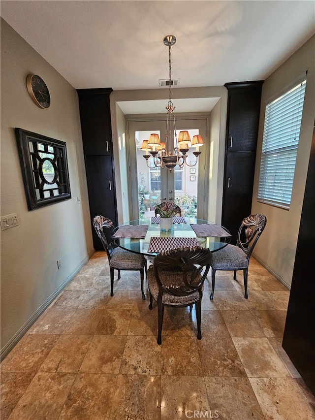 dining room with stone finish flooring, visible vents, baseboards, and an inviting chandelier