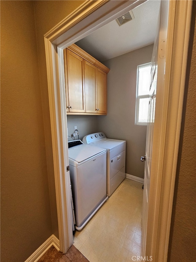 laundry area with washing machine and dryer, visible vents, baseboards, cabinet space, and light floors