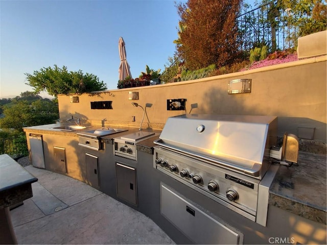 view of patio featuring exterior kitchen, a sink, and grilling area