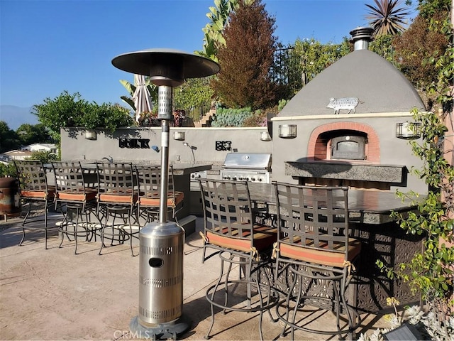 view of patio featuring a grill, a fireplace, exterior kitchen, and outdoor dining space