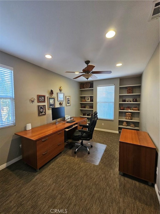 office area with baseboards, visible vents, dark colored carpet, and a wealth of natural light