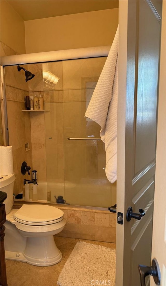 bathroom with an enclosed shower, tile patterned floors, and toilet