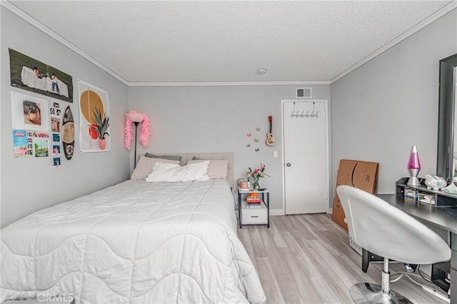 bedroom with a textured ceiling, ornamental molding, and light hardwood / wood-style floors