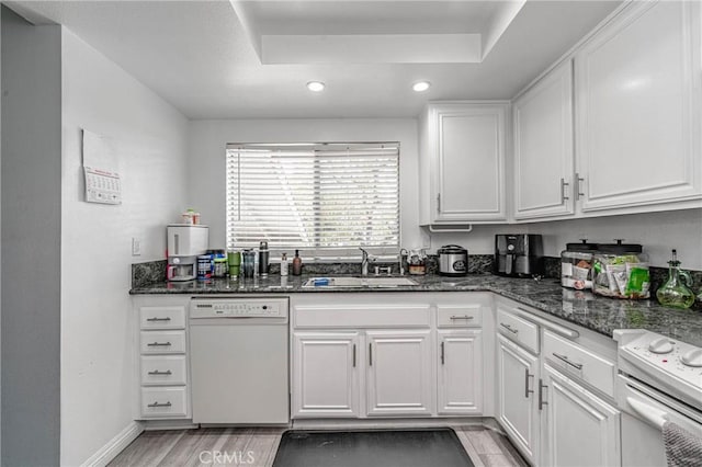 kitchen with white cabinetry, sink, dark stone countertops, and white appliances