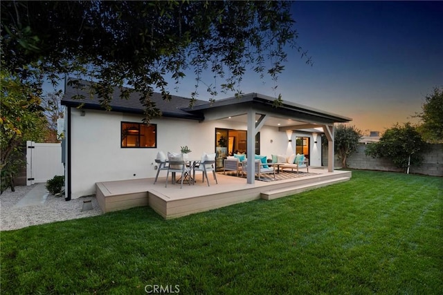 back house at dusk featuring an outdoor living space and a yard