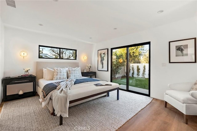 bedroom featuring access to outside, visible vents, and wood finished floors