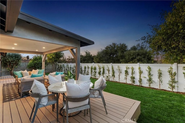 wooden deck with outdoor dining area, a fenced backyard, a lawn, and an outdoor hangout area