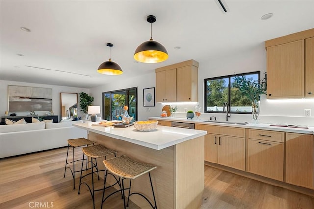 kitchen with light wood-type flooring, light countertops, a sink, and light brown cabinetry