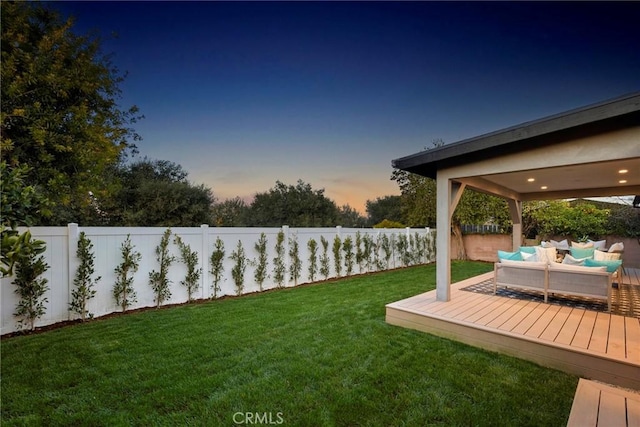 yard at dusk with a fenced backyard, an outdoor living space, and a wooden deck