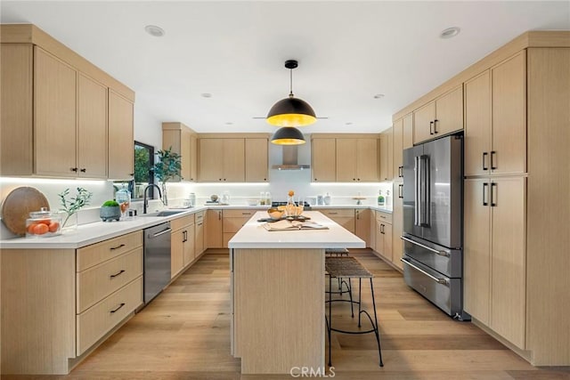 kitchen featuring appliances with stainless steel finishes, light brown cabinets, light wood finished floors, and a breakfast bar area