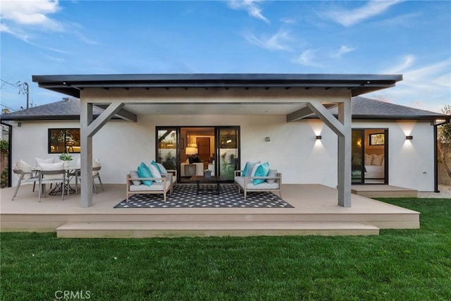 rear view of property with a deck, outdoor lounge area, a yard, roof with shingles, and stucco siding