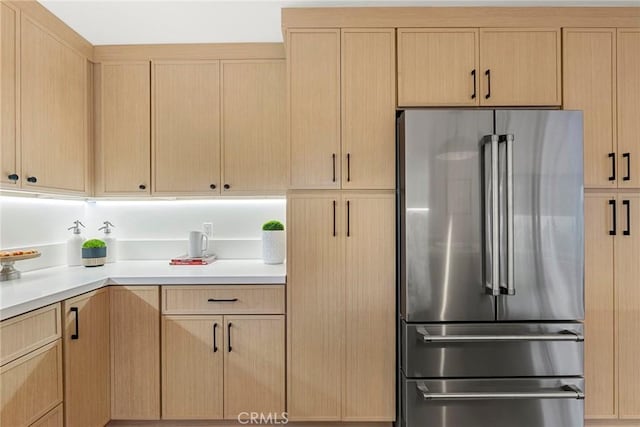 kitchen featuring light brown cabinetry, light countertops, and freestanding refrigerator