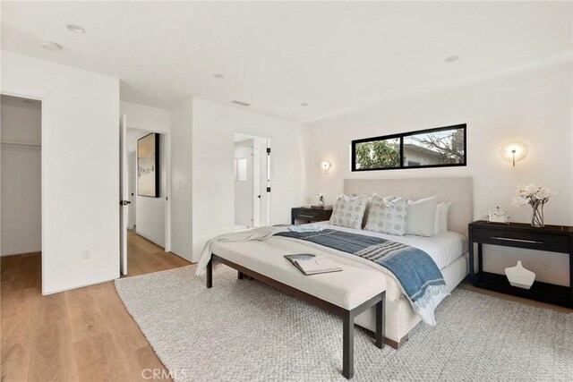 bedroom featuring a closet, a spacious closet, and light hardwood / wood-style flooring