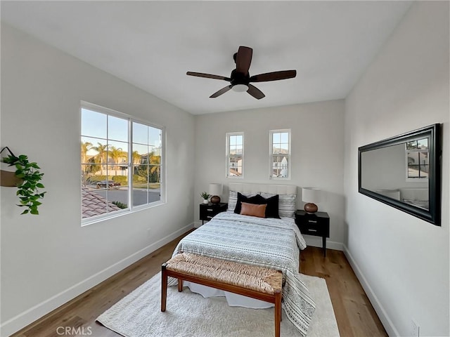 bedroom with multiple windows, wood-type flooring, and ceiling fan