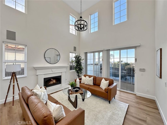 living room with an inviting chandelier, light hardwood / wood-style floors, and a high ceiling