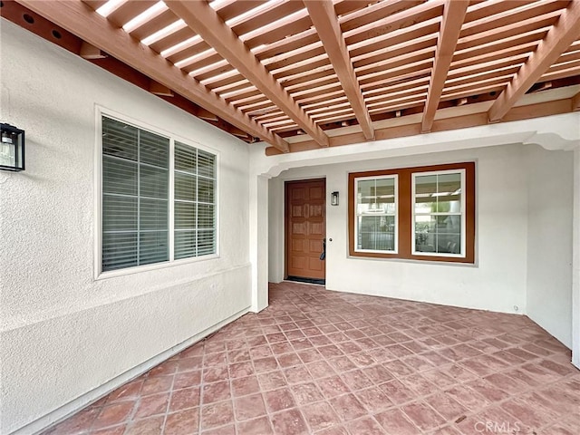 view of exterior entry with a pergola and a patio area