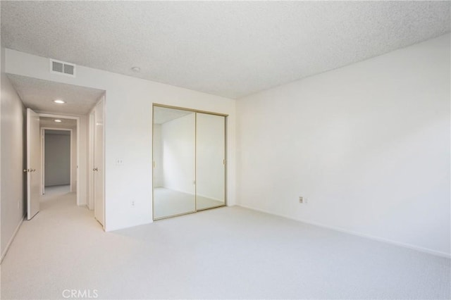 unfurnished bedroom with light colored carpet and a closet