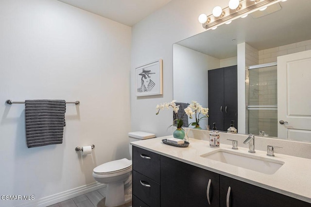 bathroom with a shower with shower door, toilet, and vanity