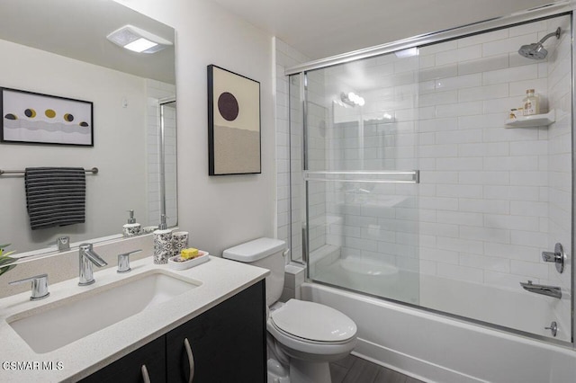 full bathroom featuring combined bath / shower with glass door, vanity, wood-type flooring, and toilet