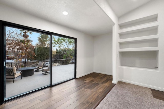 spare room featuring hardwood / wood-style flooring, lofted ceiling, and built in features