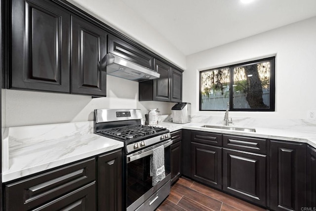 kitchen with gas stove, light stone countertops, sink, and wall chimney exhaust hood