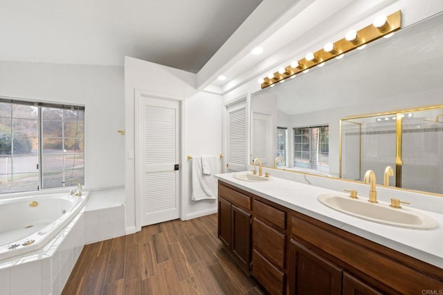 bathroom with vanity, independent shower and bath, vaulted ceiling, and hardwood / wood-style floors