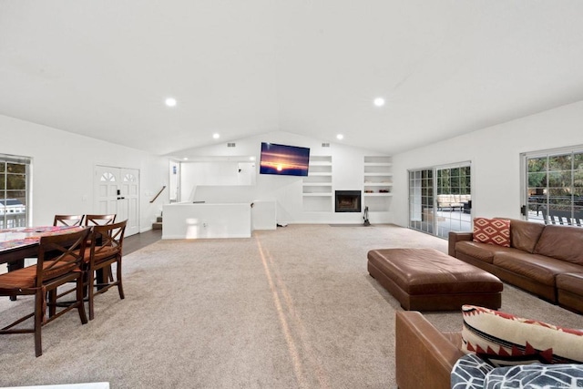 carpeted living room with built in shelves and vaulted ceiling