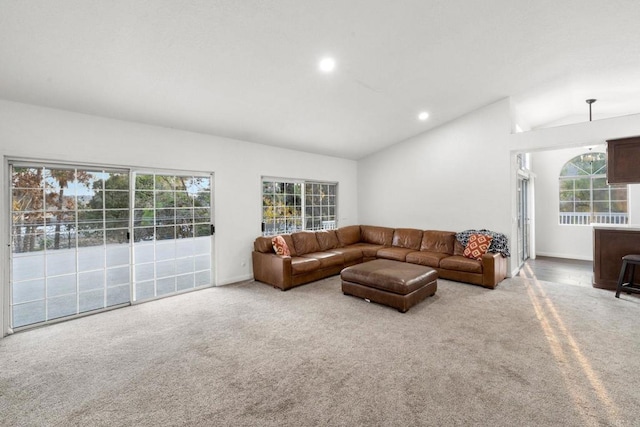 living room featuring lofted ceiling, a healthy amount of sunlight, and light colored carpet