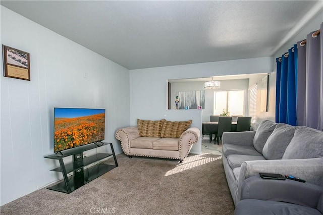 carpeted living room featuring an inviting chandelier