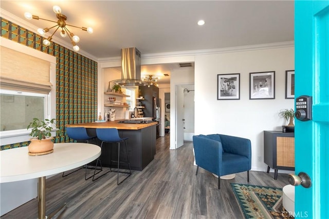 kitchen featuring dark hardwood / wood-style flooring, an inviting chandelier, a kitchen breakfast bar, ornamental molding, and butcher block countertops