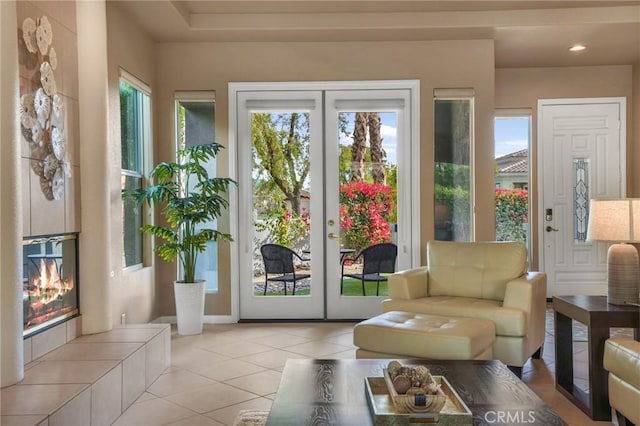 doorway to outside featuring a tile fireplace, light tile patterned flooring, a wealth of natural light, and french doors