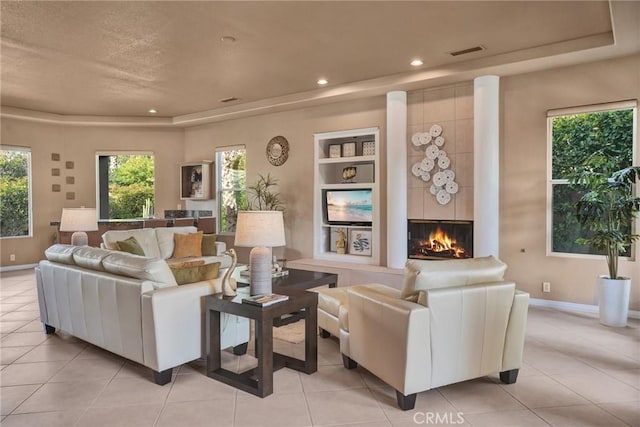 living room featuring built in shelves, a raised ceiling, and light tile patterned flooring