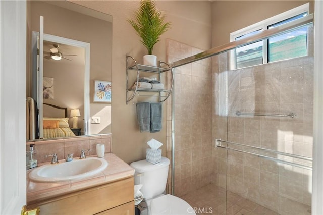 bathroom with toilet, vanity, ceiling fan, and a shower with shower door