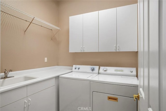 washroom featuring sink, washing machine and dryer, and cabinets